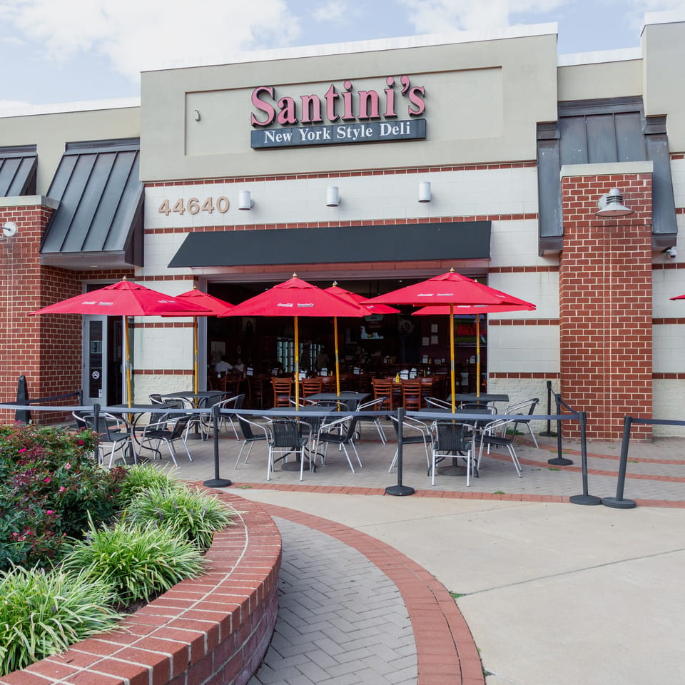 Santini's New York Style Deli exterior with red umbrellas shading outdoor seating on a sunny day.