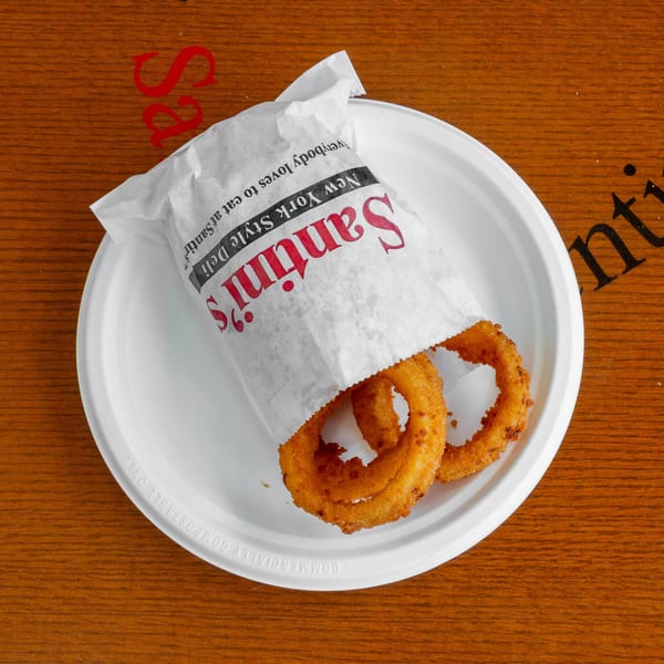 Crispy onion rings in a Santini's New York Style Deli paper bag on a white plate.