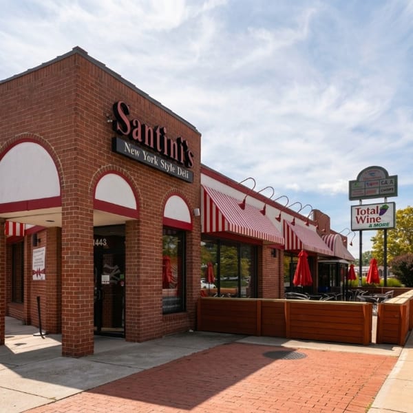 Exterior of Santini's New York Style Deli with red brick, striped awnings, and outdoor patio seating.