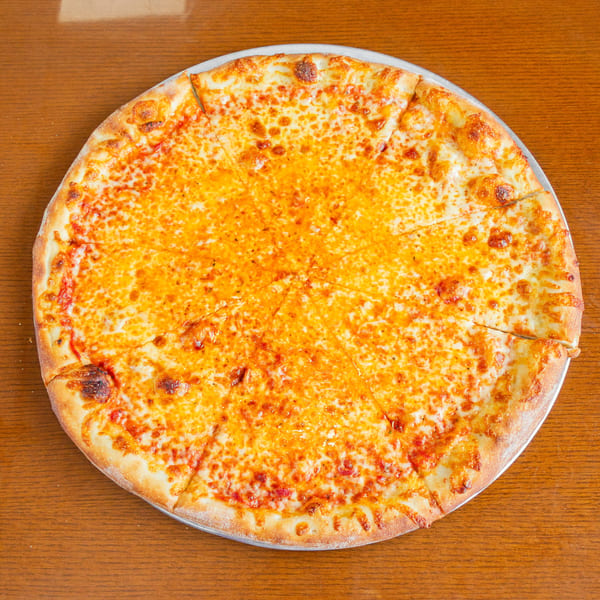 A whole cheese pizza, cut into slices, on a metal pan atop a wooden table.