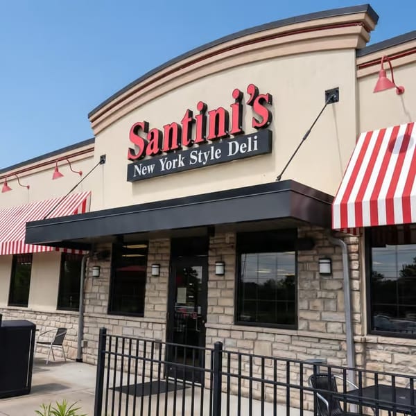 Santini's New York Style Deli storefront with red sign, striped awnings, and outdoor seating.