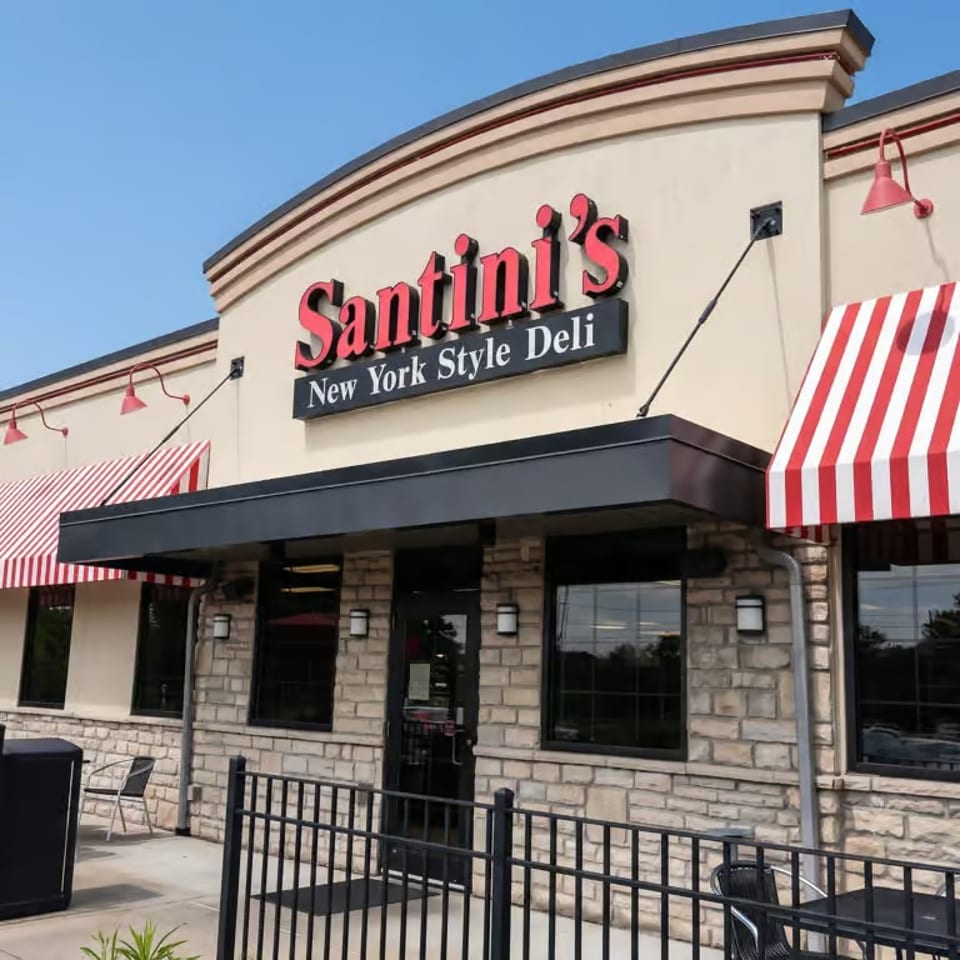 Santini's New York Style Deli storefront with red sign, striped awnings, and outdoor seating.